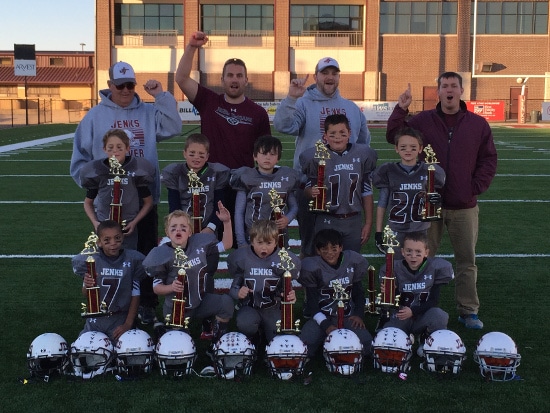 A championship trophy of little footballers with their coaches in ground.