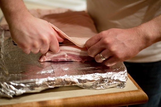 A man skinning a raw pork on slab. 