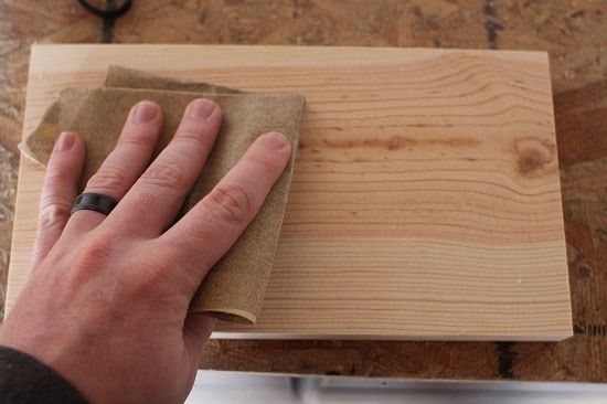 The man is smoothing the surface of the pine.