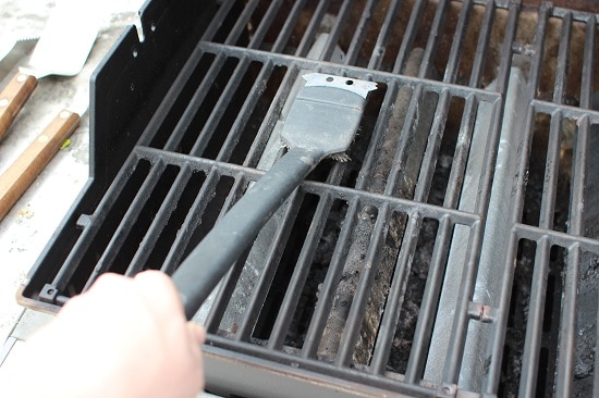 Nettoyage des grilles du gril avec une brosse métallique.