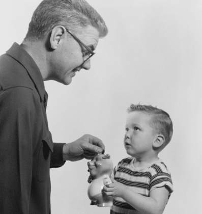 vintage dad putting coin into son's piggy bank 