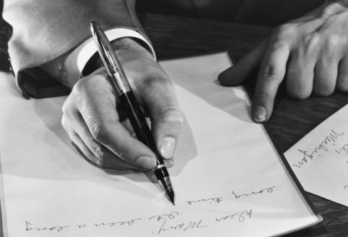 A man using fountain pen to write on paper. 