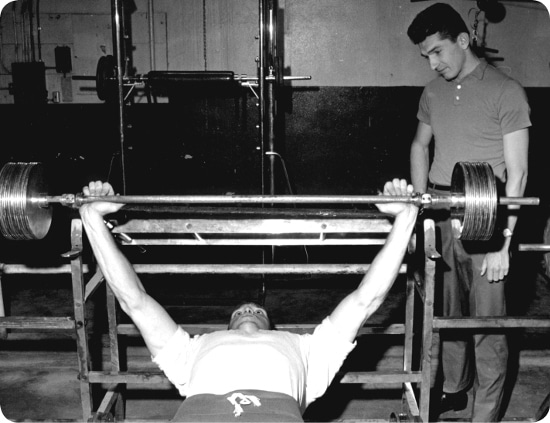 Tips for newbies at the gym: A man performing a bench press with a barbell.