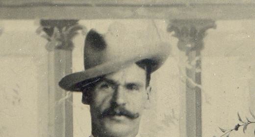 An old photo of a man with scars wearing a hat.