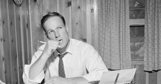 A man sitting at a desk with a typewriter.
