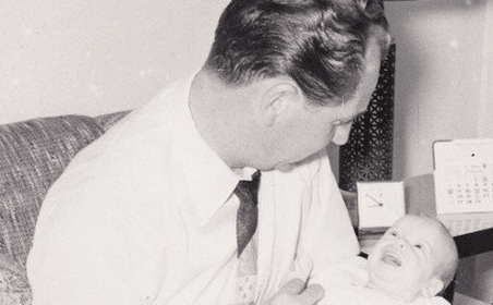 An old photo of a father holding a baby.