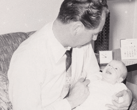 An old photo of a father holding a baby.