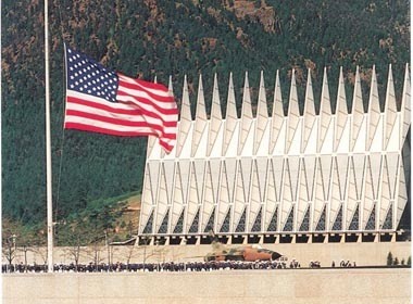 A group of American men standing in front of a building with an American flag.
