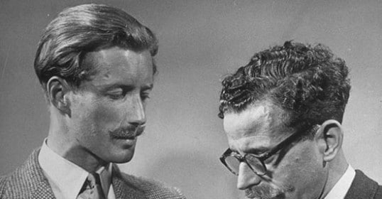 Two men are admiring each other's ties, noticing the minor differences.