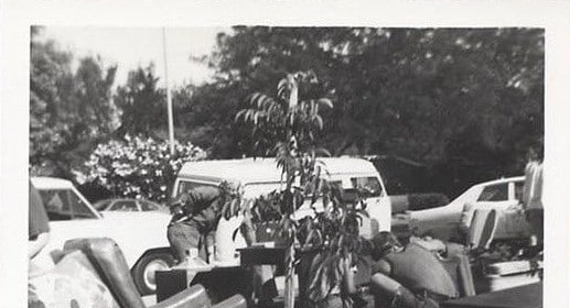A black and white photo of a group of people sitting in the grass.