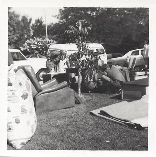 A black and white photo of a group of people sitting in the grass.