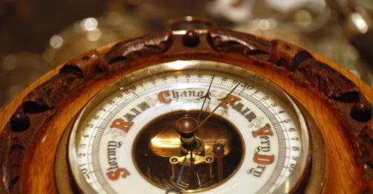 A close up of a clock with a sundial, giving a forecast for the weather.