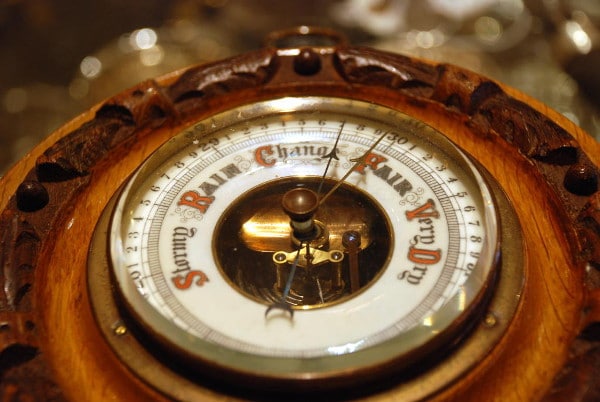 A close up of a clock with a sundial, giving a forecast for the weather.