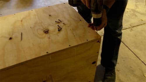 Screwing plywood boards together to make a box.