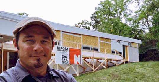 A carpenter standing in front of a house under construction.