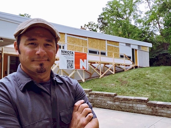 A carpenter standing in front of a house under construction.