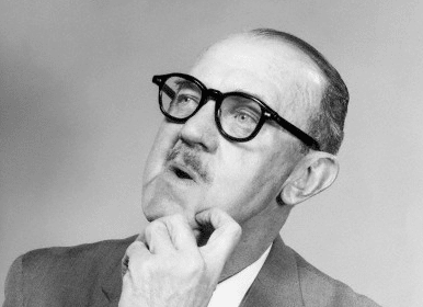 This is a black and white photo of a man wearing glasses and a suit.