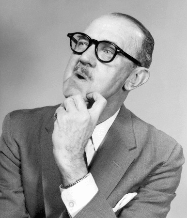 This is a black and white photo of a man wearing glasses and a suit.