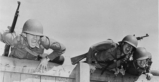 Three tough soldiers leaning over a fence after completing military fitness training.