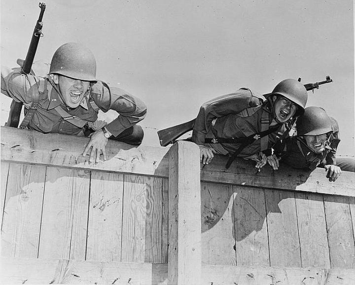 Three tough soldiers leaning over a fence after completing military fitness training.