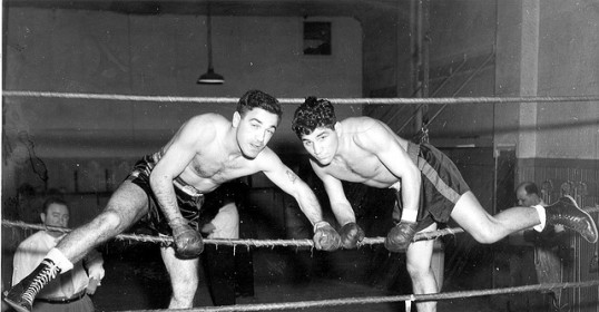 Two men in a boxing ring display their testosterone levels through their intense aggression.