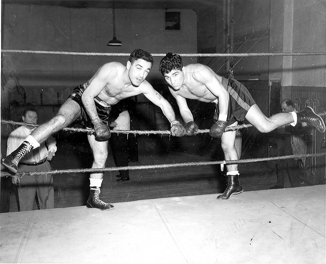 Two men in a boxing ring display their testosterone levels through their intense aggression.
