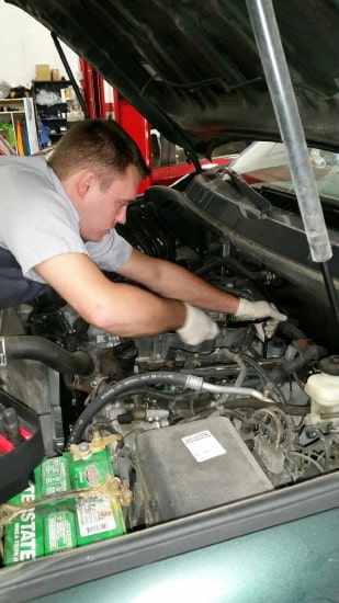 Jesse adams car mechanic technician working under hood wearing gloves.