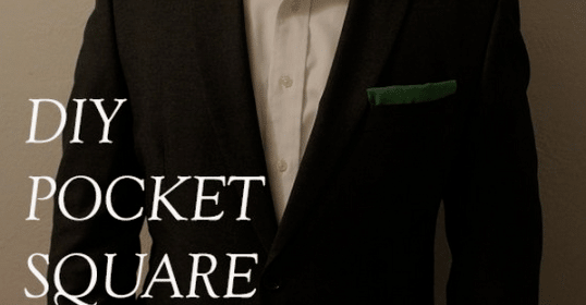 A man in a suit showcasing his DIY pocket square, no sewing required.