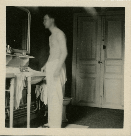 Vintage young man looking in mirror washroom bathroom.