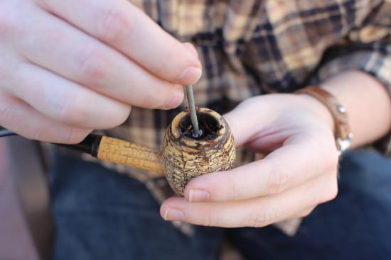 Tamping pipe tobacco with nail corn cob pipe.