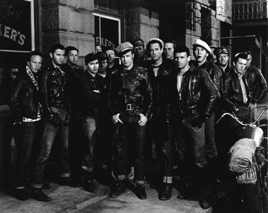 A group of men in leather jackets, exuding a rebel cool vibe, standing in front of a building.