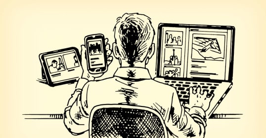 A man sitting at a desk with a laptop and cell phone to stay connected.