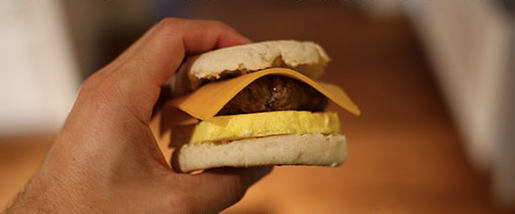 An image of a person holding a sandwich, showcasing the convenience of Make-Ahead Breakfast Sandwiches for saving time and money.