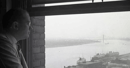 An old black and white photo of a man looking out of a window, his visions ahead.
