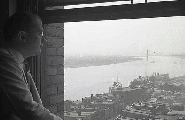 An old black and white photo of a man looking out of a window, his visions ahead.