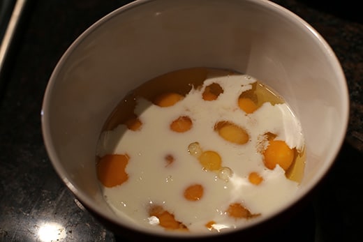Adding milk to eggs in bowl.