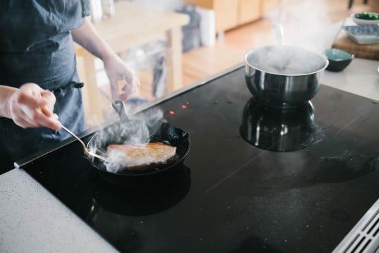 Chef Sarah is cooking chicken breast on iron stove. 