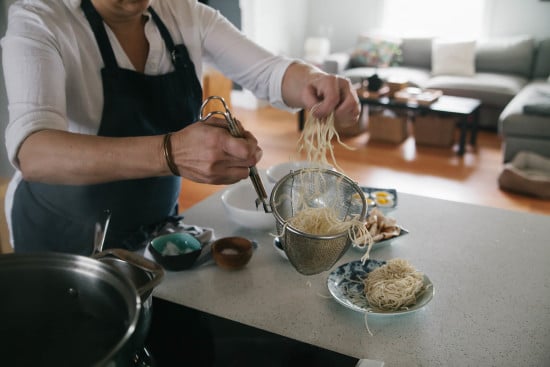 Chef Sarah is putting cooked ramen noodles into large bowl. 