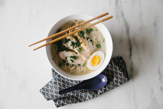 Homemade ramen in large bowl with chicken egg and sticks. 