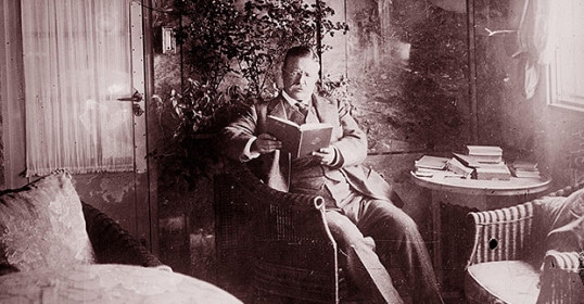 A man sitting in a chair, engrossed in reading.