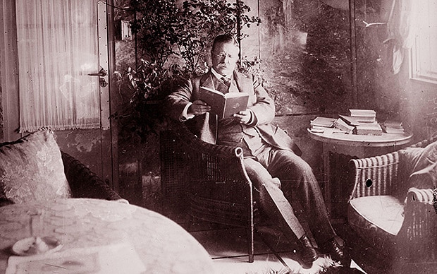 A man sitting in a chair, engrossed in reading.