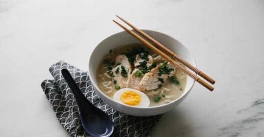 An authentic bowl of ramen with a softly boiled egg and chopsticks.