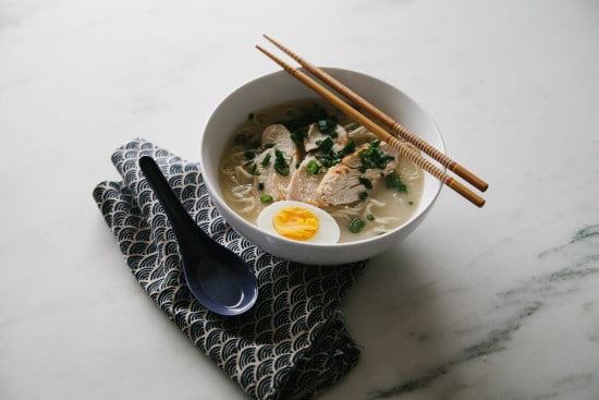 An authentic bowl of ramen with a softly boiled egg and chopsticks.