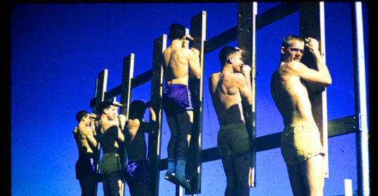 A group of men standing on a wooden wall during a Podcast recording.