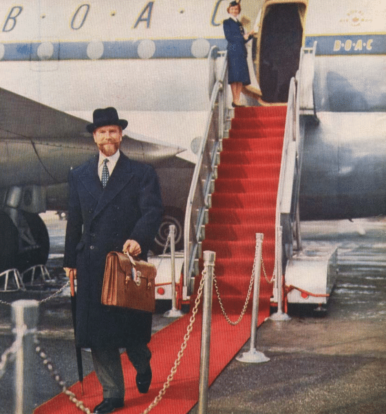 A man in a suit walking down a red carpet for a job.