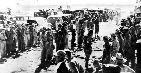 A group of people, including a man, standing in a line on a dirt road.