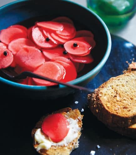 Pickled Radishes in bowl and bread slice at the table.