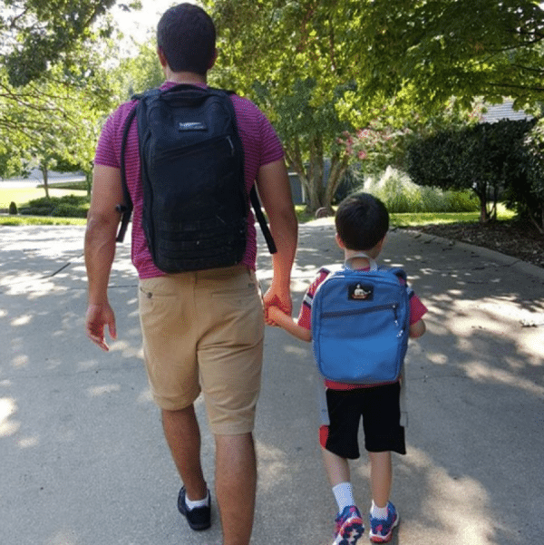 dadwalking with son down street with backpacks 