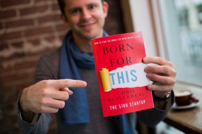 A man holding up a book called "Born for This.