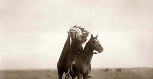 An old photograph of a native american man on horseback.